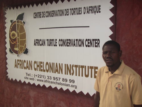Marcel (Rhodin Center employee) next to the entrance sign of the Rhodin Center